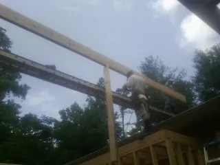 Carpenter setting a ridge beam over a new addition frame — Ice Dam Removal by Roofing Brothers in Saxton