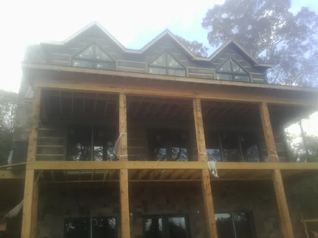 Dormers and porch framing on a large log home under construction — Roof Coating work by our crew in Saxton