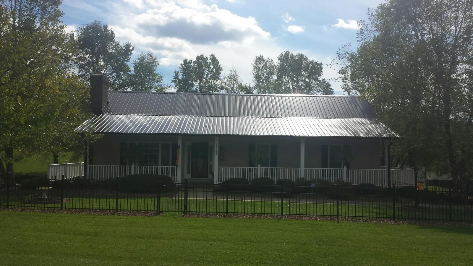 Gray metal roof on a brick ranch with a full width front porch — Gutter Guard Installation work by our crew in Saxton