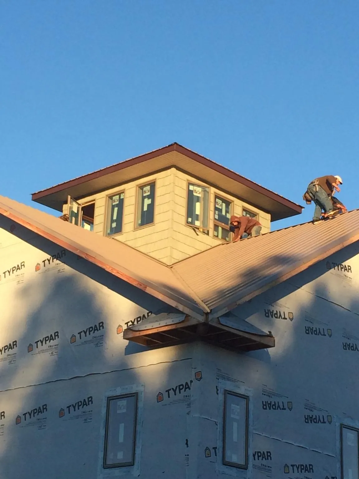 Roofers working around a rooftop cupola on a new metal roof at sunset — Roof Waterproofing in Saxton by Roofing Brothers